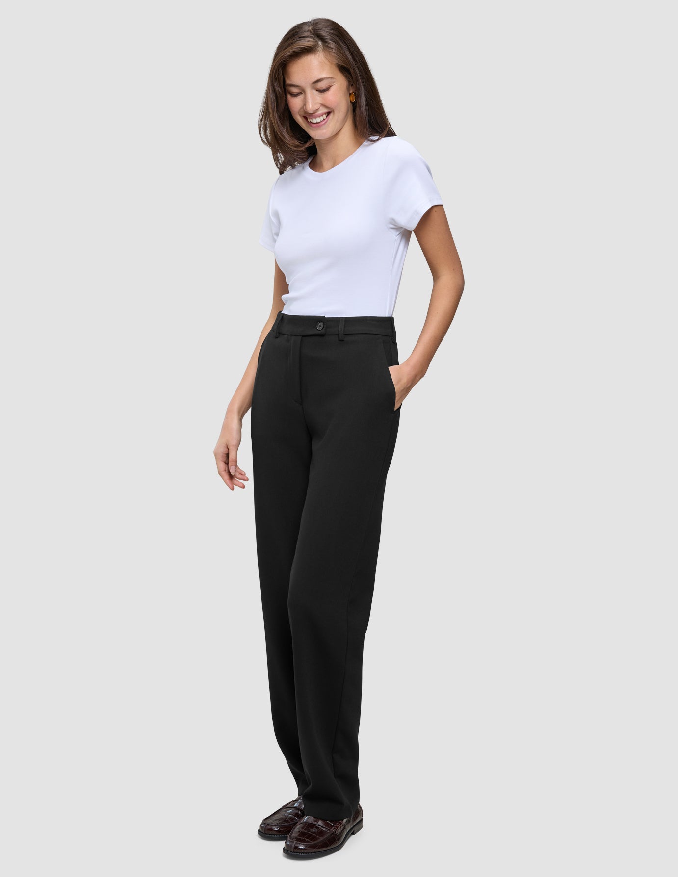 En kvinne iført en hvit T-skjorte og Women GO2 Pants Straight Black i klassisk skandinavisk design.