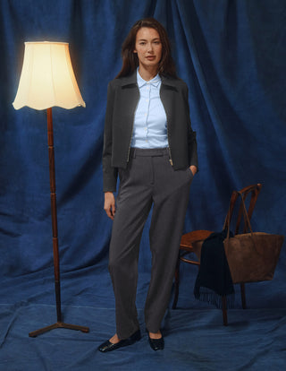 En kvinne har på seg en mørkegrå jakke, en lyseblå skjorte med knapper og Women GO2 Pants Straight Dark Grey Melange.