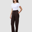 En kvinne i en hvit T-skjorte og et par Women GO2 Pants Straight i fargen mocha, med hånden i lommen.