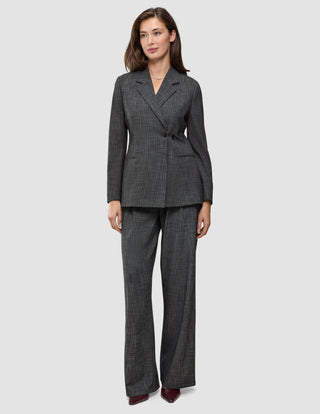 En kvinne har på seg en Women Nara Blazer Fitted Black Check i mørkegrå rutemønster, sammen med matchende bukser med vid benåpning og 360°-stretch.