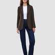 En person har på seg en brun Women Serene Blazer Regular Walnut Herringbone, en hvit T-skjorte og mørkeblå jeans.