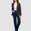 En kvinne kledd i en Women Serene Blazer Regular Walnut Herringbone, en hvit T-skjorte og mørkeblå jeans.