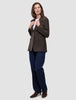 En kvinne har på seg en Women Serene Blazer Regular i valnøttfarget fiskebeinmønster over en hvit skjorte og blå jeans, noe som gjenspeiler en klassisk stil.