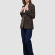 En kvinne har på seg en Women Serene Blazer Regular i valnøttfarget fiskebeinmønster over en hvit skjorte og blå jeans, noe som gjenspeiler en klassisk stil.