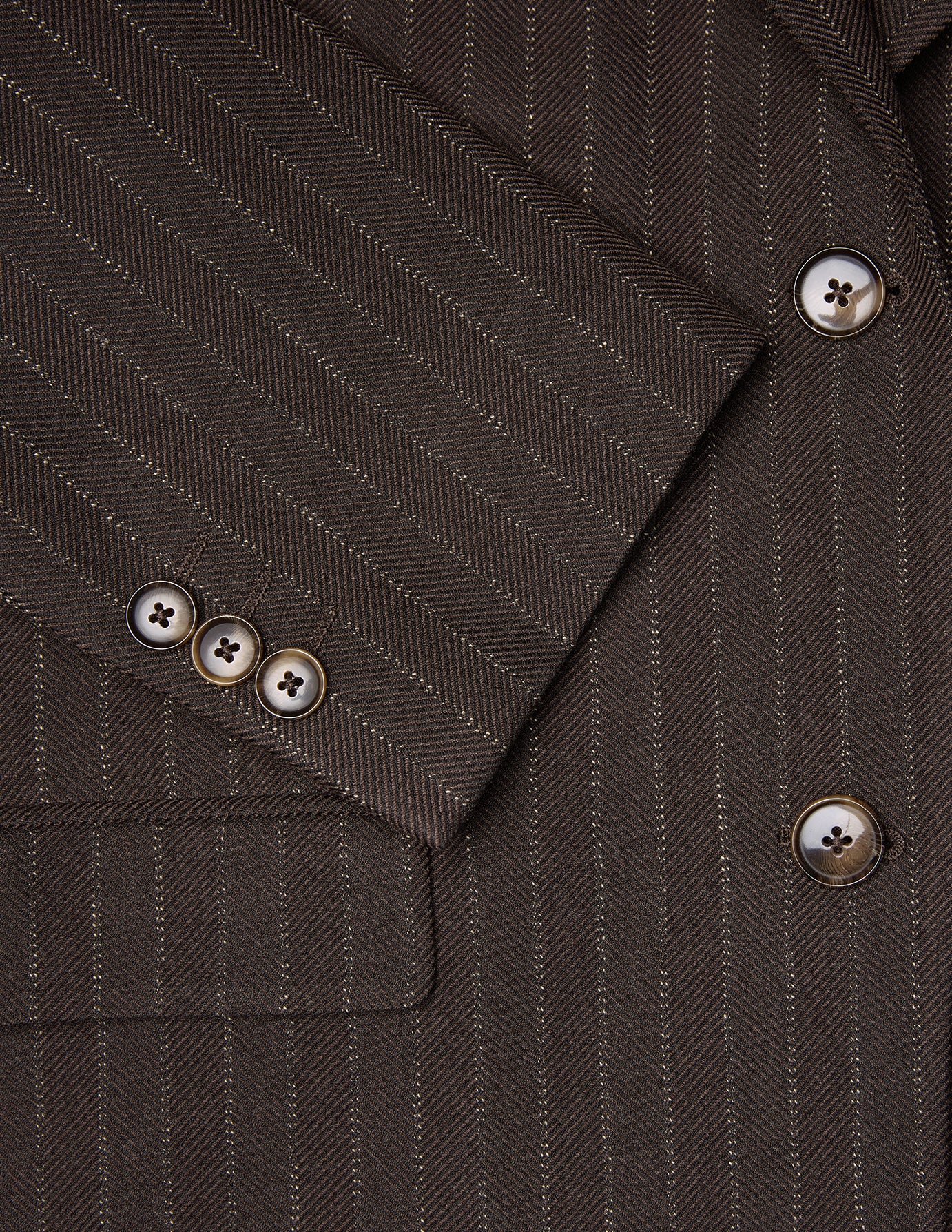 Kvinneblazer Serene i vanlig passform, Walnut Herringbone – i brunt fiskebeinmønster med vertikale nålestriper og mansjetter med fire knapper.