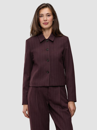 En kvinne iført en Women Serene Short Jacket Berry Pinstripe, med et minimalistisk design og knappelukking.