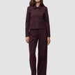 En kvinne har på seg en Women Serene Short Jacket Berry Pinstripe sammen med matchende bukser med vide ben i mørkt stoff med tynne striper.