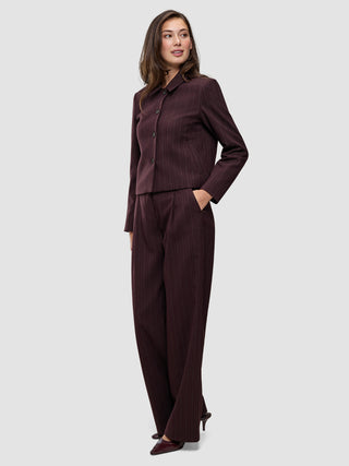 En kvinne kledd i en minimalistisk Women Serene Short Jacket Berry Pinstripe og matchende bukser med vide ben.