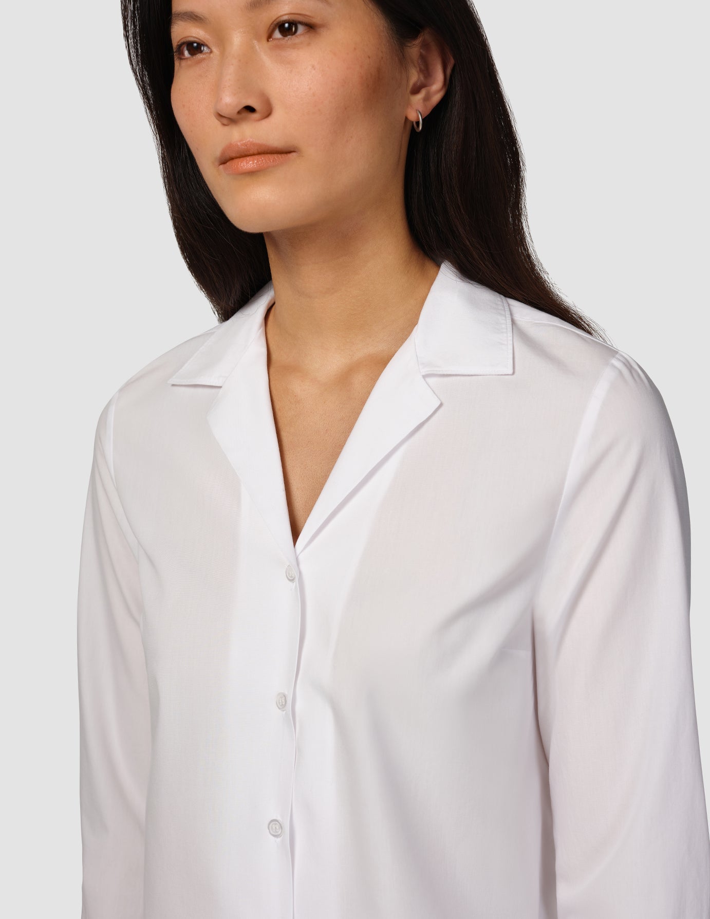 En kvinne har på seg en «Madison Shirt White», en hvit skjorte med lange ermer og knappestolpe samt en skjorte med utskåret krage.