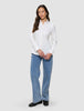 En kvinne iført en Women’s Oxford Shirt White Orchid Slim, som hun har stappet inn i lyseblå jeans og svarte loafers.