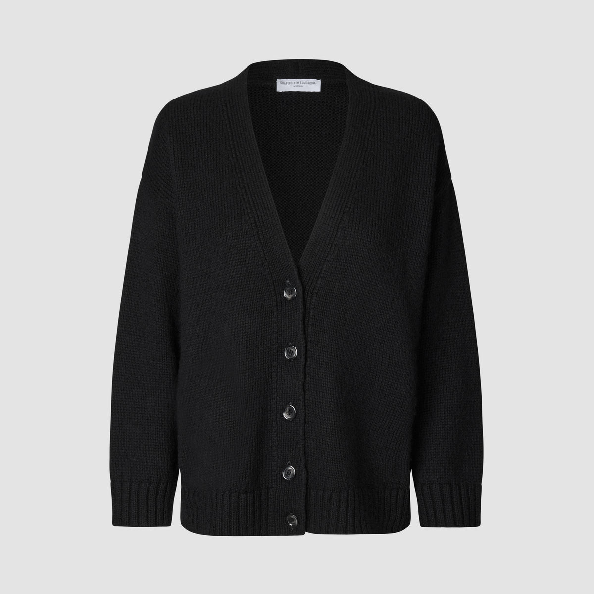 Kvinners tykk, myk ullstrikket cardigan i svart: en modell med V-hals og knapper foran, samt ribbestrikkede mansjetter og nederkant.