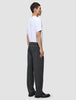En mann sett i profil har på seg en hvit T-skjorte og Atelier Pants Relaxed Dark Grey i mørkegrå, løstsittende brutt twill.