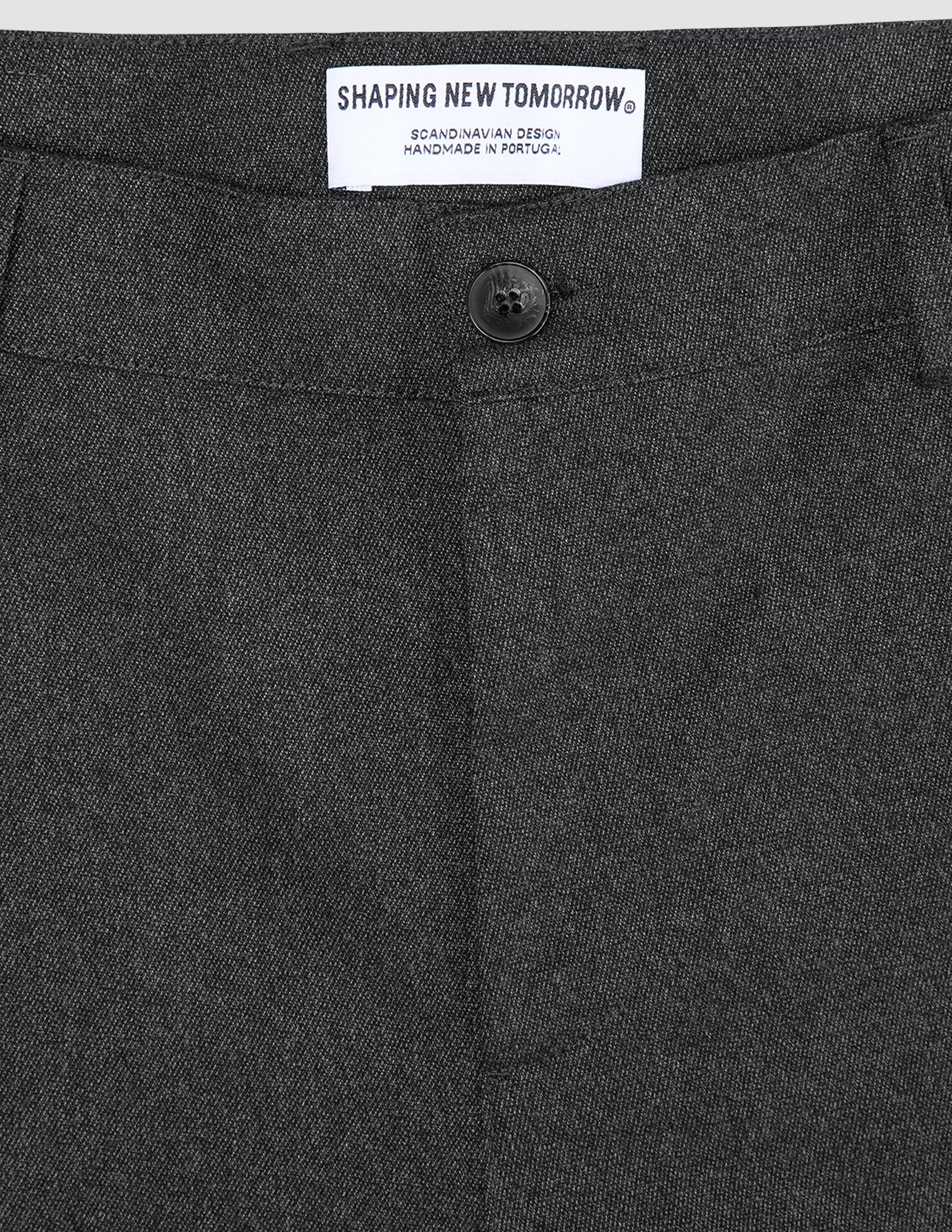 Mørkegrå Atelier-bukse i brutt twill, med en svart knapp og SHAPING NEW TOMORROW-merke.