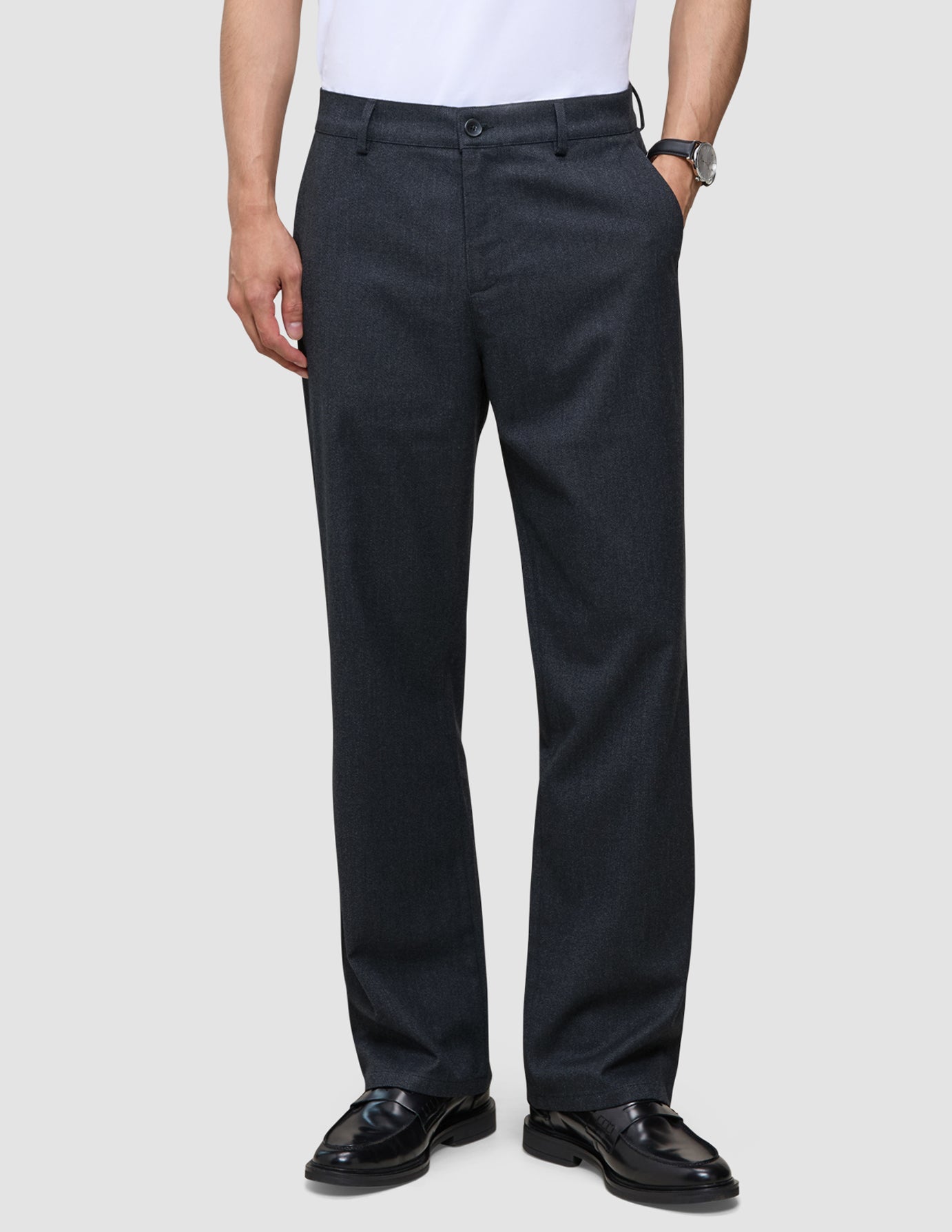 En person som har på seg mørkeblå Atelier Pants Relaxed Dark Navy i brutt twill og sorte skinnloafers.