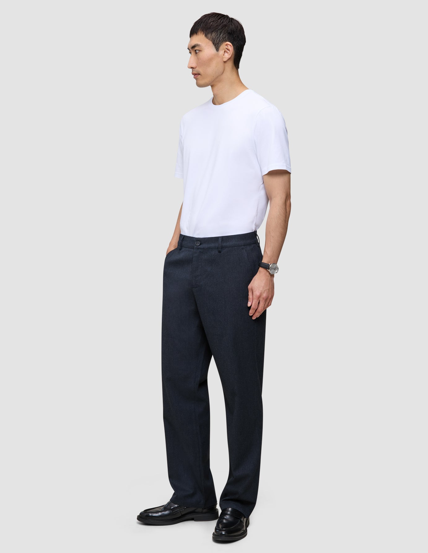 En mann kledd i en hvit T-skjorte og Atelier Pants Relaxed Dark Navy i brutt twill-vev.