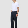 En mann kledd i en hvit T-skjorte og Atelier Pants Relaxed Dark Navy i brutt twill-vev.