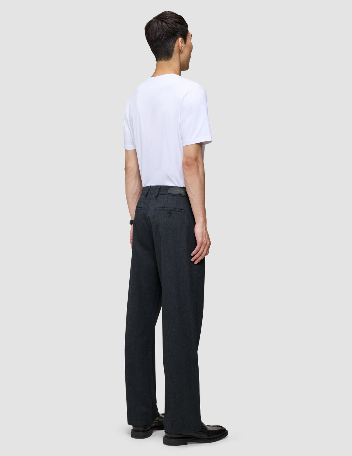 En person sett bakfra, kledd i en hvit T-skjorte og mørk marineblå Atelier Pants Relaxed.