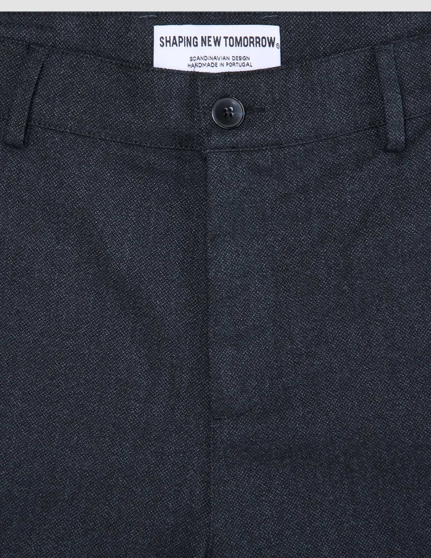 Nærbilde av de mørkeblå Atelier Pants Relaxed-buksene, som viser stoffet i brutt twill, knappelukking og innvendig merkelapp.