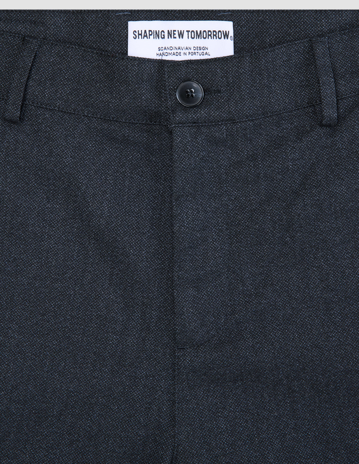 Nærbilde av de mørkeblå Atelier Pants Relaxed-buksene, som viser stoffet i brutt twill, knappelukking og innvendig merkelapp.