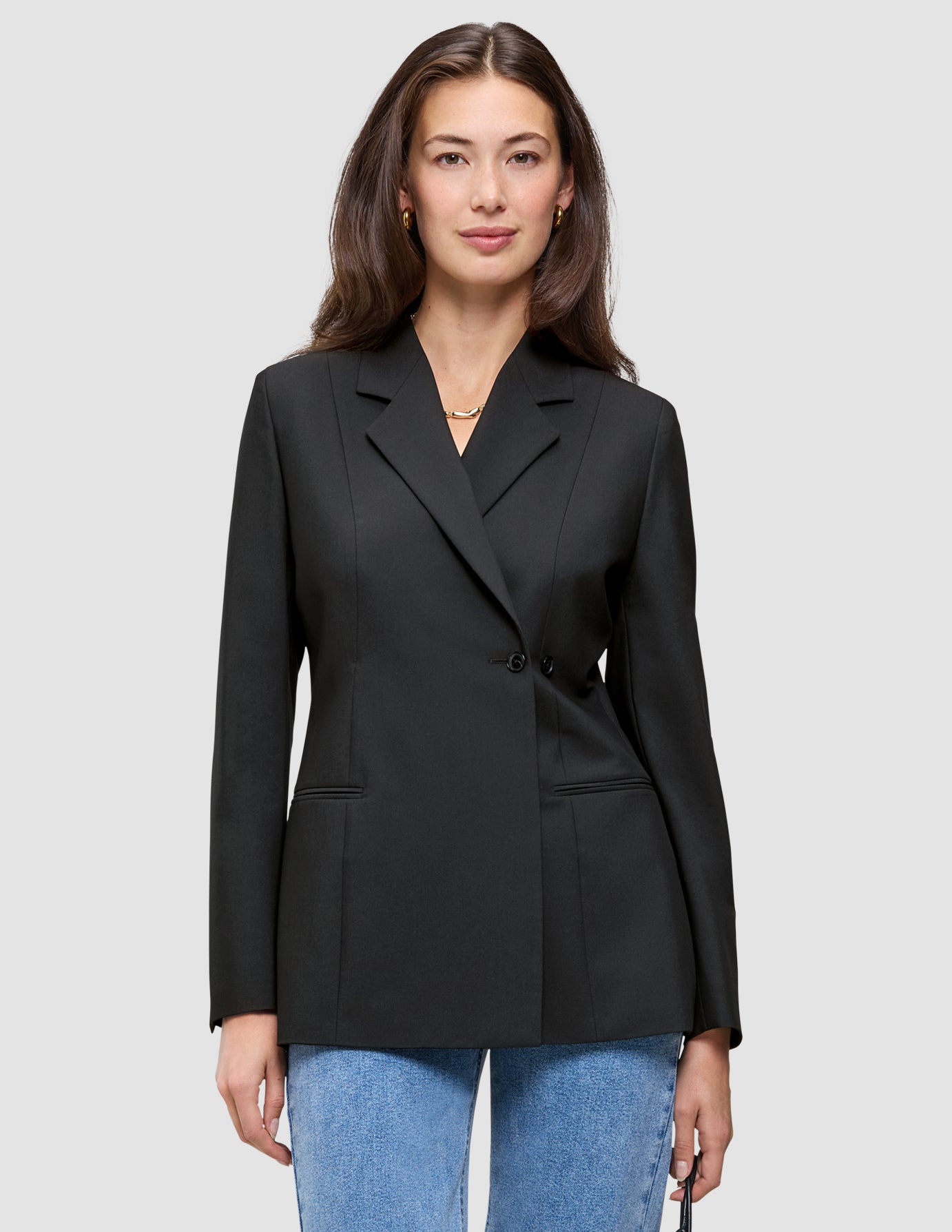En kvinne har på seg en svart Women’s Avira Blazer Black med én knapp over blå jeans.