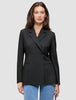 En kvinne har på seg en svart Women’s Avira Blazer Black med én knapp over blå jeans.