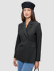 En kvinne som har på seg en svart Women’s Avira Blazer Black med dobbeltradet snitt og en svart beret.