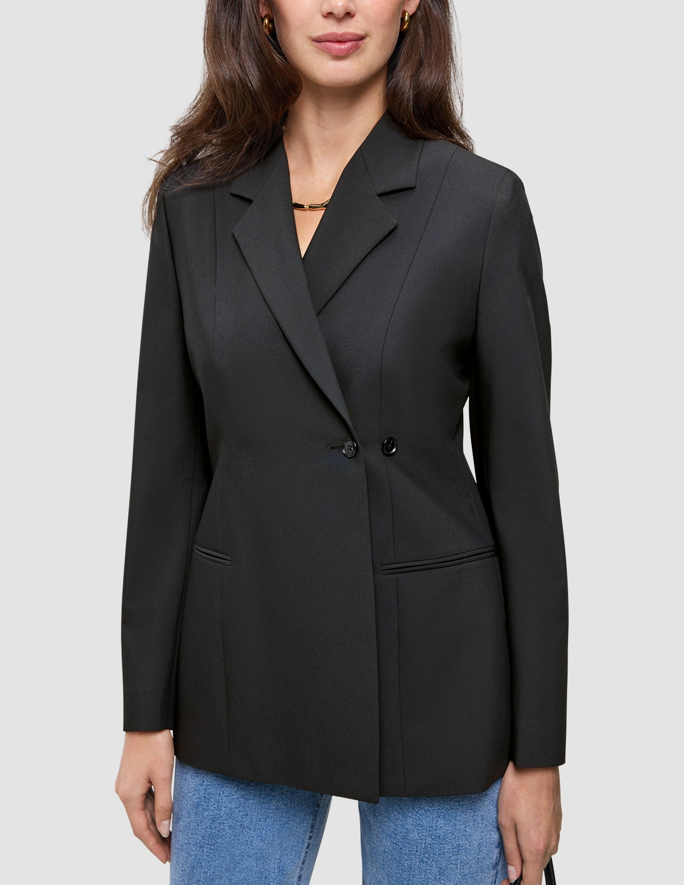 En kvinne som har på seg en svart, dobbeltradet Women’s Avira Blazer-blazer over blå jeans.