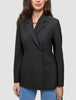 En kvinne som har på seg en svart, dobbeltradet Women’s Avira Blazer-blazer over blå jeans.