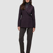 En kvinne som har på seg en Women’s Avira Blazer Burgundy Berry over en grå turtleneck og mørke bukser med svarte høyhælte sko.