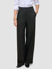 En person som har på seg svarte Avira Pants Wide for damer og en hvit skjorte med knapper.