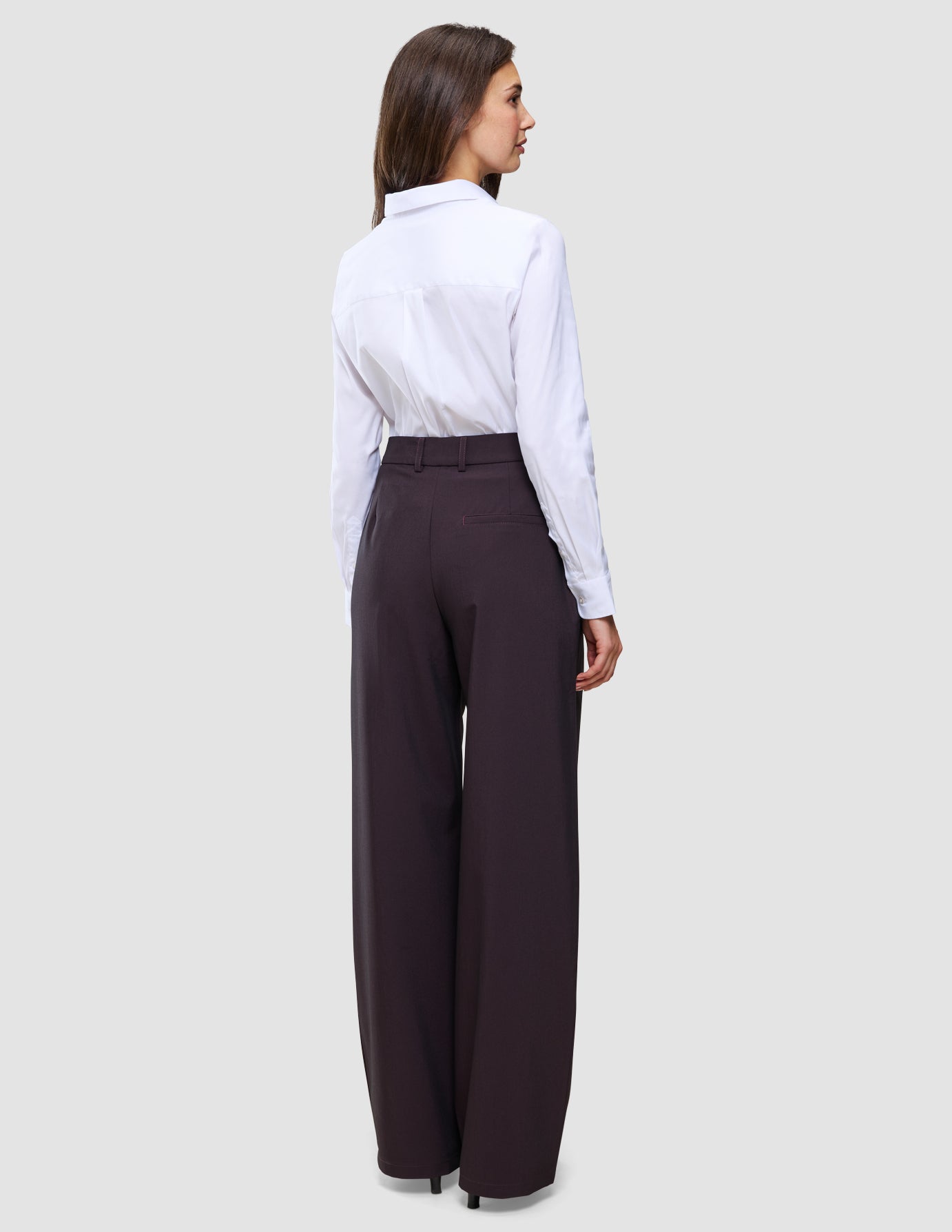En kvinne kledd i en hvit skjorte med knapper og et par Women’s Avira Pants Wide Burgundy Berry-bukser med høy midje.