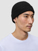 En person som har på seg en svart Beanie Black-lue i et skandinavisk ribbestrikket mønster.