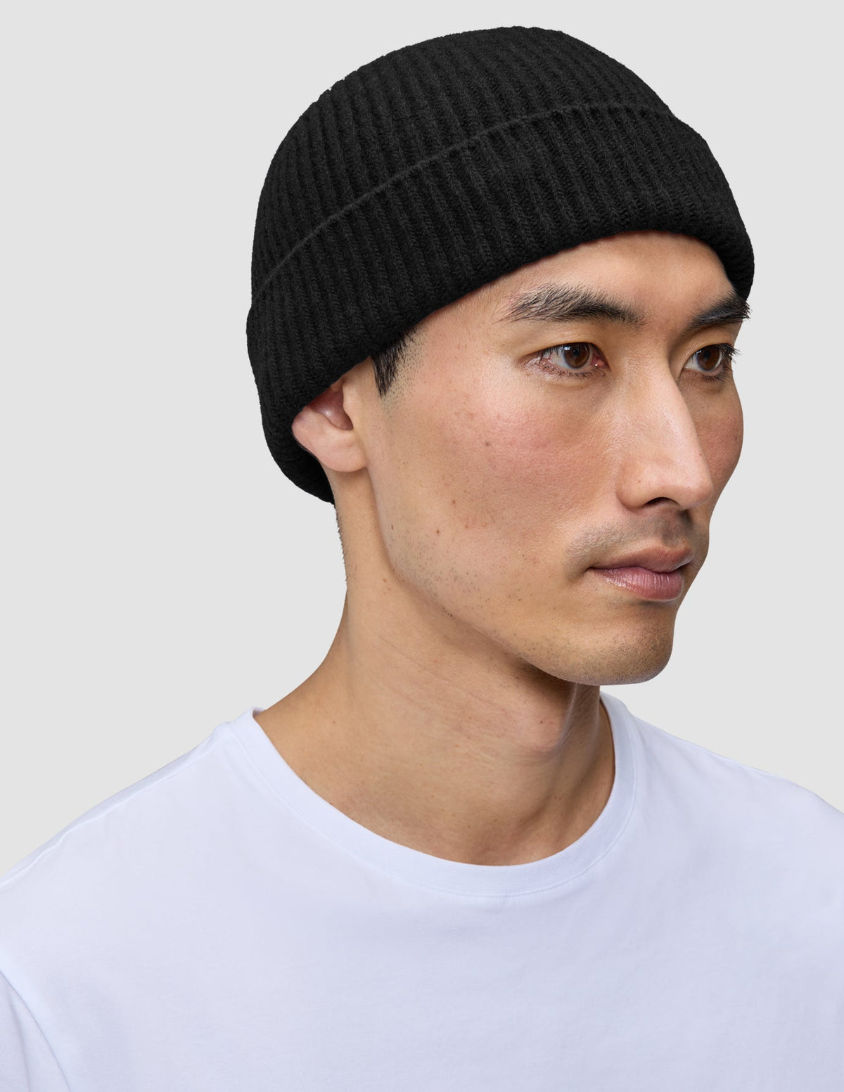 En person som har på seg en svart Beanie Black-lue i et skandinavisk ribbestrikket mønster.