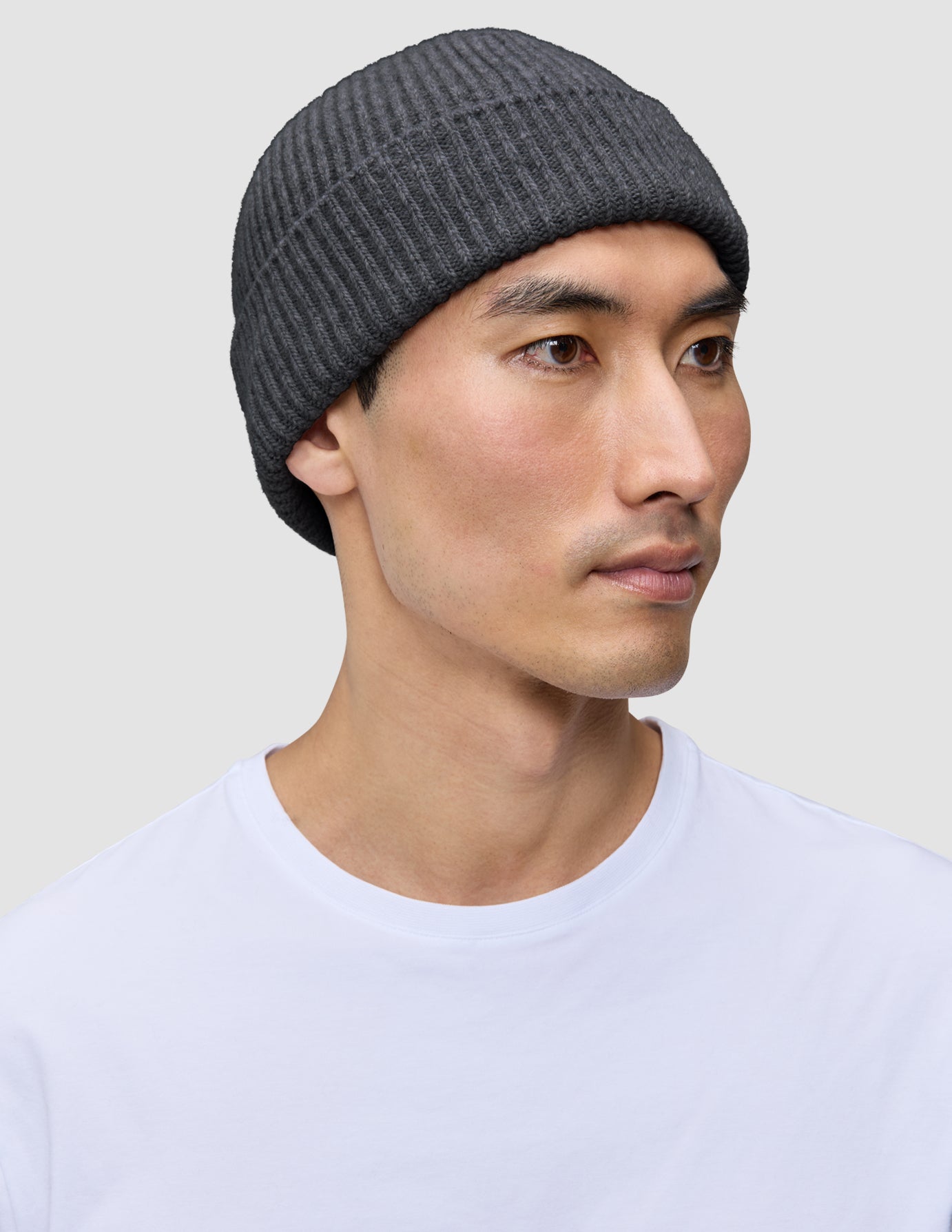 En person som har på seg en mørkegrå lue (Beanie Dark Grey) i et klassisk skandinavisk ribbestrikket design.