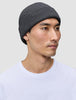 En person som har på seg en mørkegrå lue (Beanie Dark Grey) i et klassisk skandinavisk ribbestrikket design.