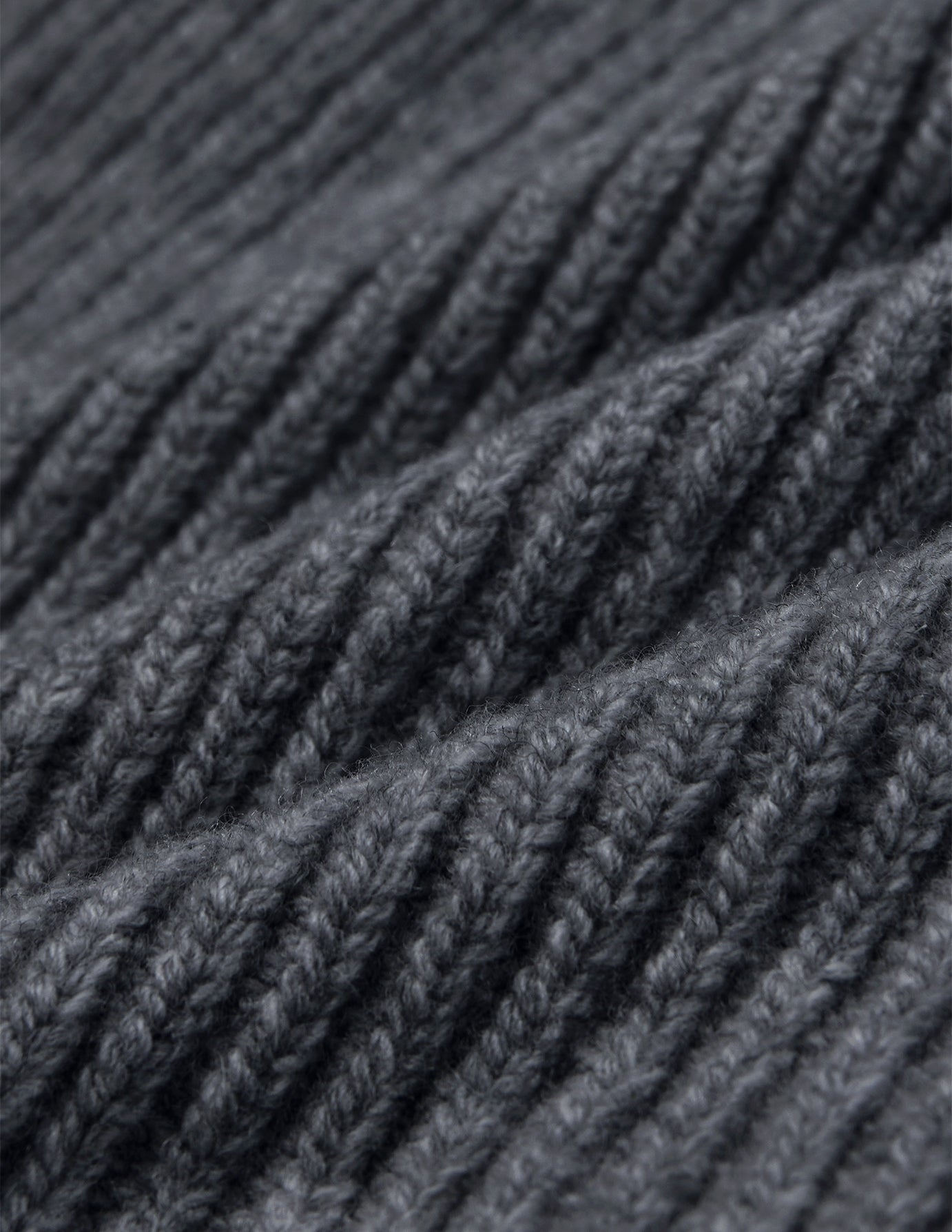 Nærbilde av en mørkegrå lue (Beanie Dark Grey) i ribbestrikket stoff.