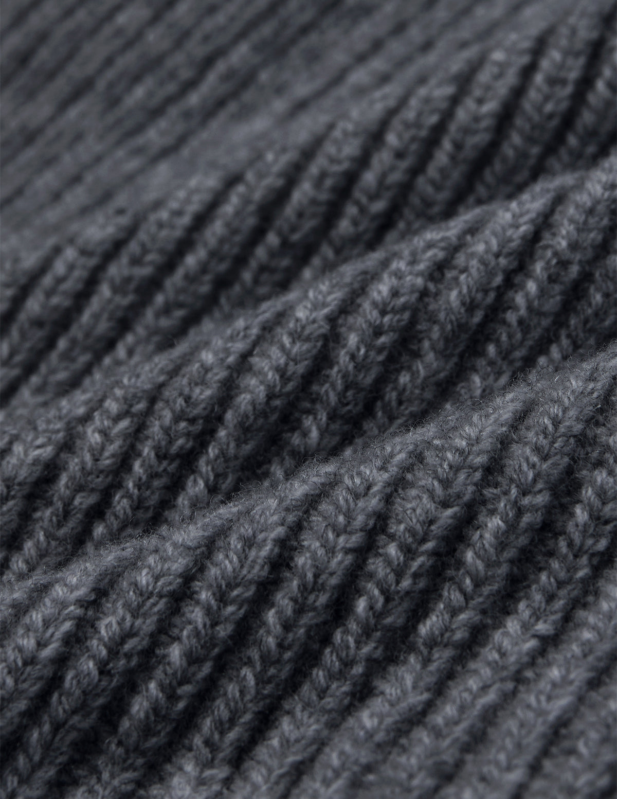 Nærbilde av en mørkegrå lue (Beanie Dark Grey) i ribbestrikket stoff.