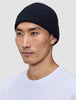 En mann som har på seg en marineblå Wool Beanie Navy i ribbestrikket design.