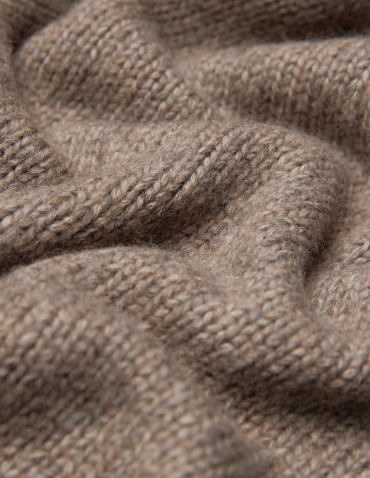 Nærbilde av en tykk, myk strikket damekardigan i taupe-melange, med en tykk, ribbet struktur i beige.