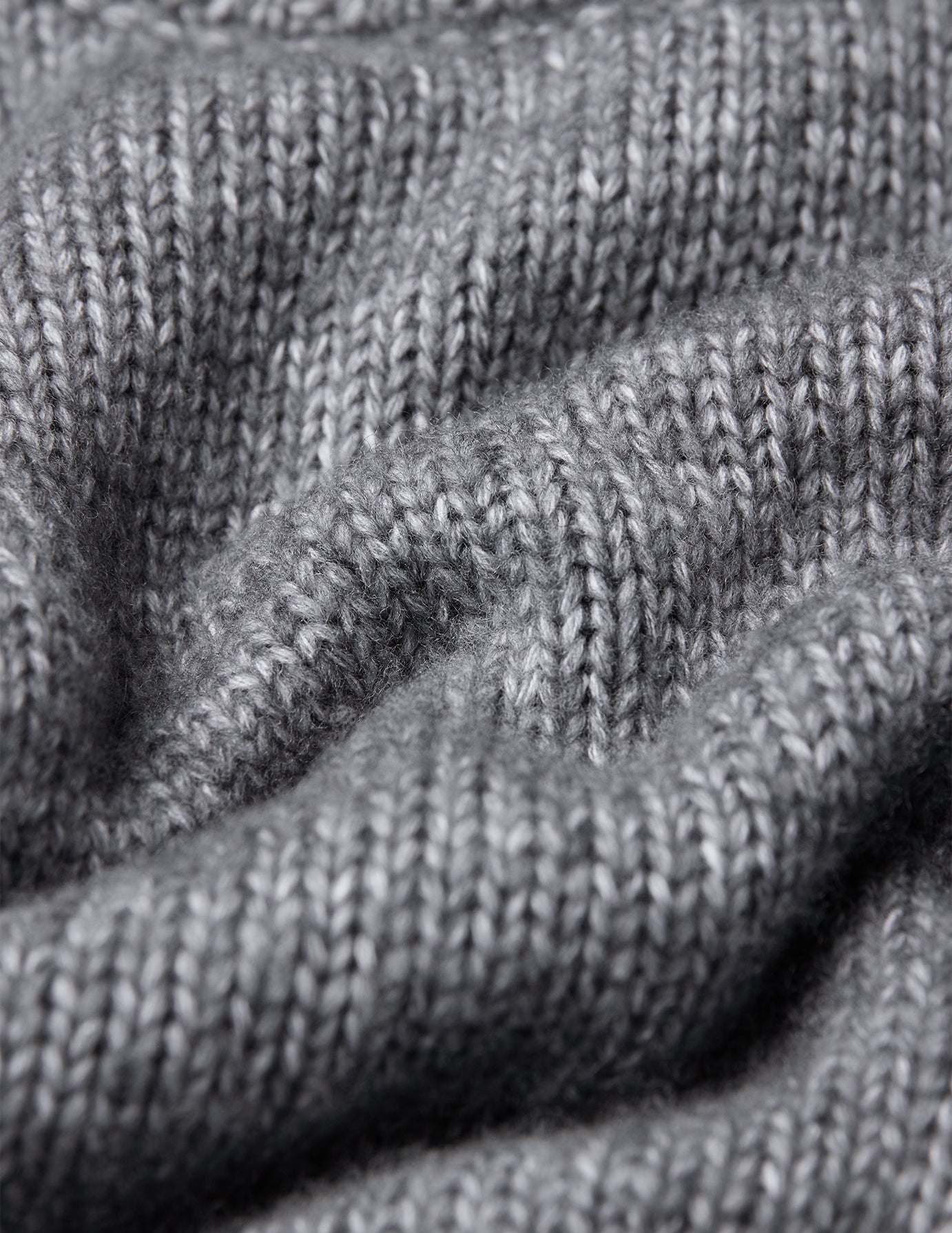 Nærbilde av en grå, tykk og myk ullgenser med rund hals i fargen Glacier Grey og skandinavisk design.