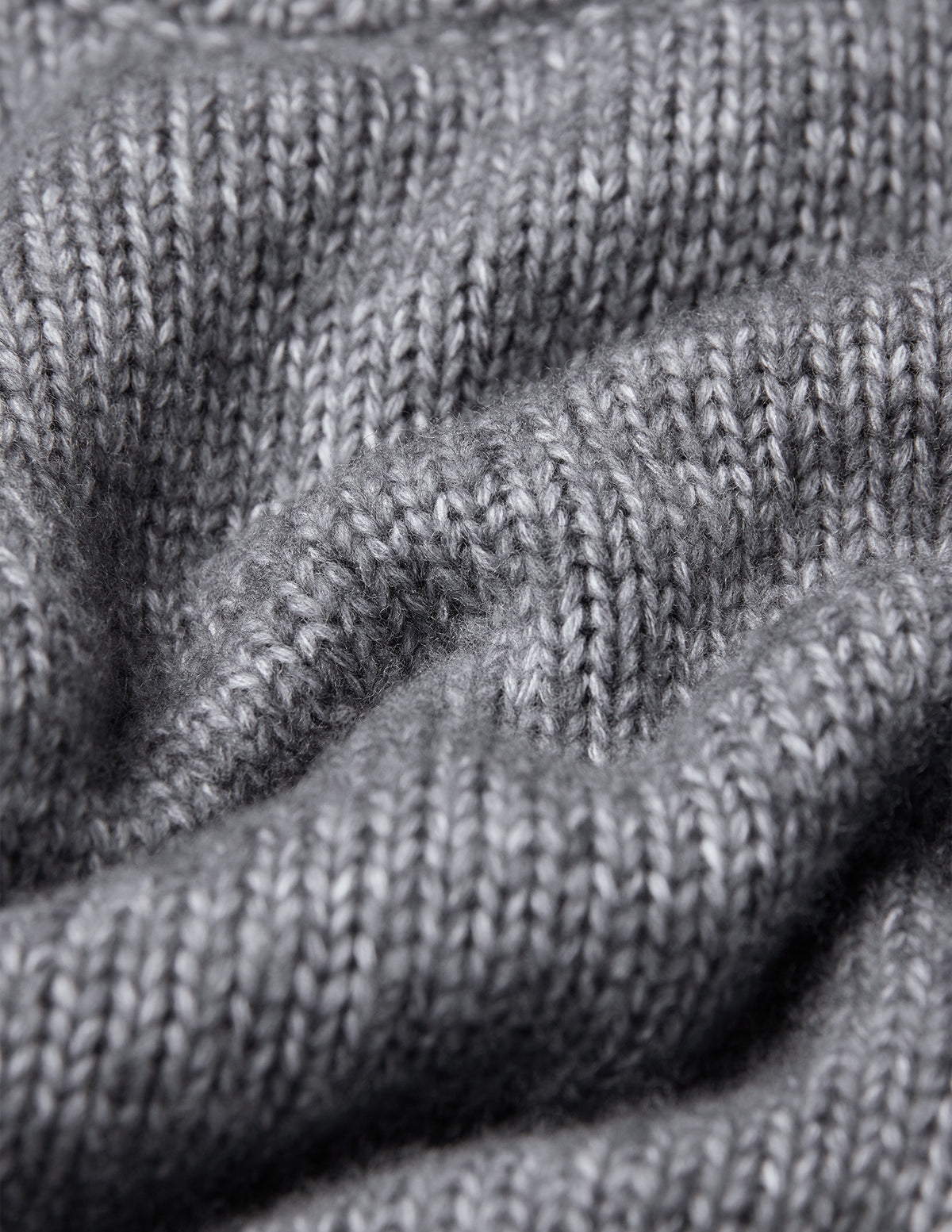 Nærbilde av en grå, tykk og myk ullgenser med rund hals i fargen Glacier Grey og skandinavisk design.