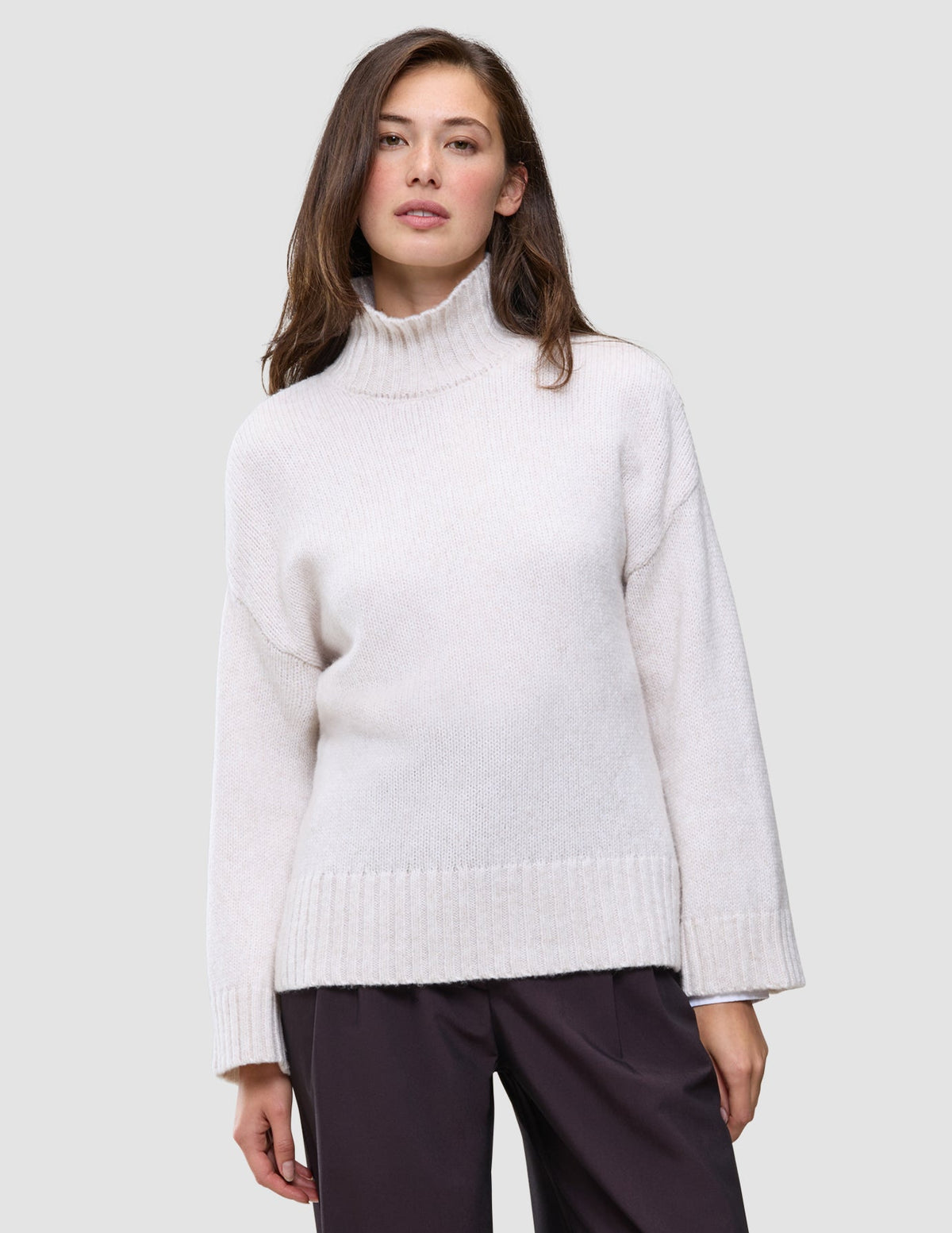 En kvinne iført en off-white, grovstrikket damegenser med høyhals i myk ull, Chunky Soft Wool Knit Turtleneck Sugar Melange.
