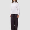 En kvinne kledd i en Women’s Chunky Soft Wool Knit Turtleneck Sugar Melange og mørke bukser med vide ben.