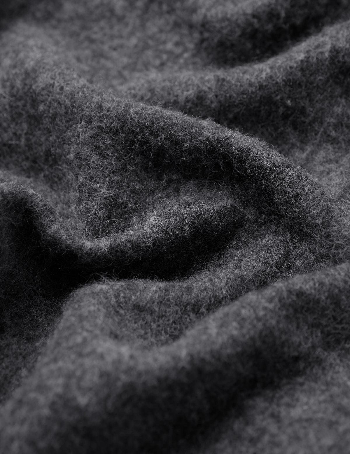 Nærbilde av en brettet, mørkegrå Double Layer Wool Overshirt Regular Dark Grey-skjorte i et stoff med en lodden tekstur.