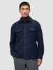 En mann har på seg en dobbeltsidig ullskjorte i mørk marineblå i standardpassform over en brun turtleneck, noe som gjenspeiler et minimalistisk design.