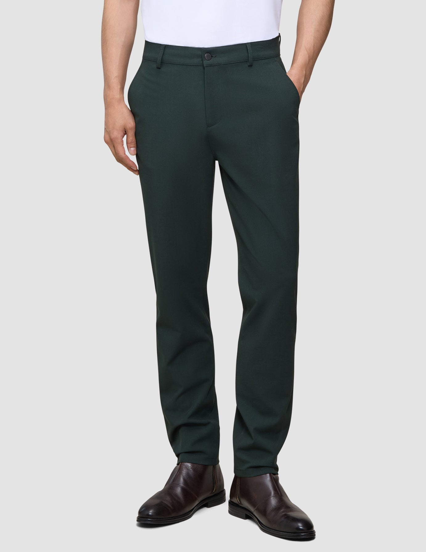 En person som har på seg mørkegrønne Ease Pants Regular Northern Pine og brune lærstøvler.
