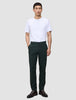 En mann har på seg en hvit T-skjorte, Ease Pants Regular Northern Pine og mørke skinnsko i en minimalistisk skandinavisk stil.