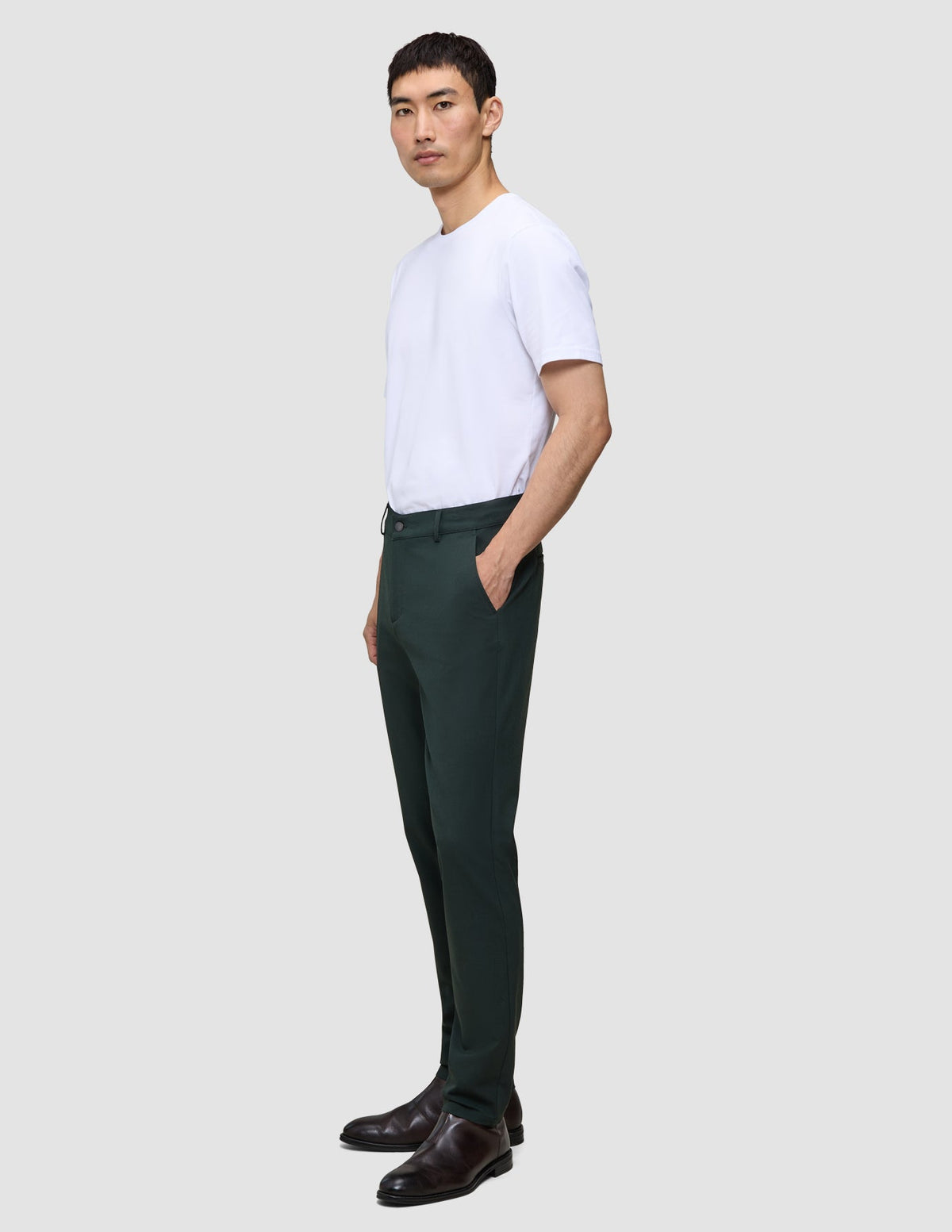 En mann i en hvit T-skjorte og Northern Pine Ease Pants Regular står i profil.