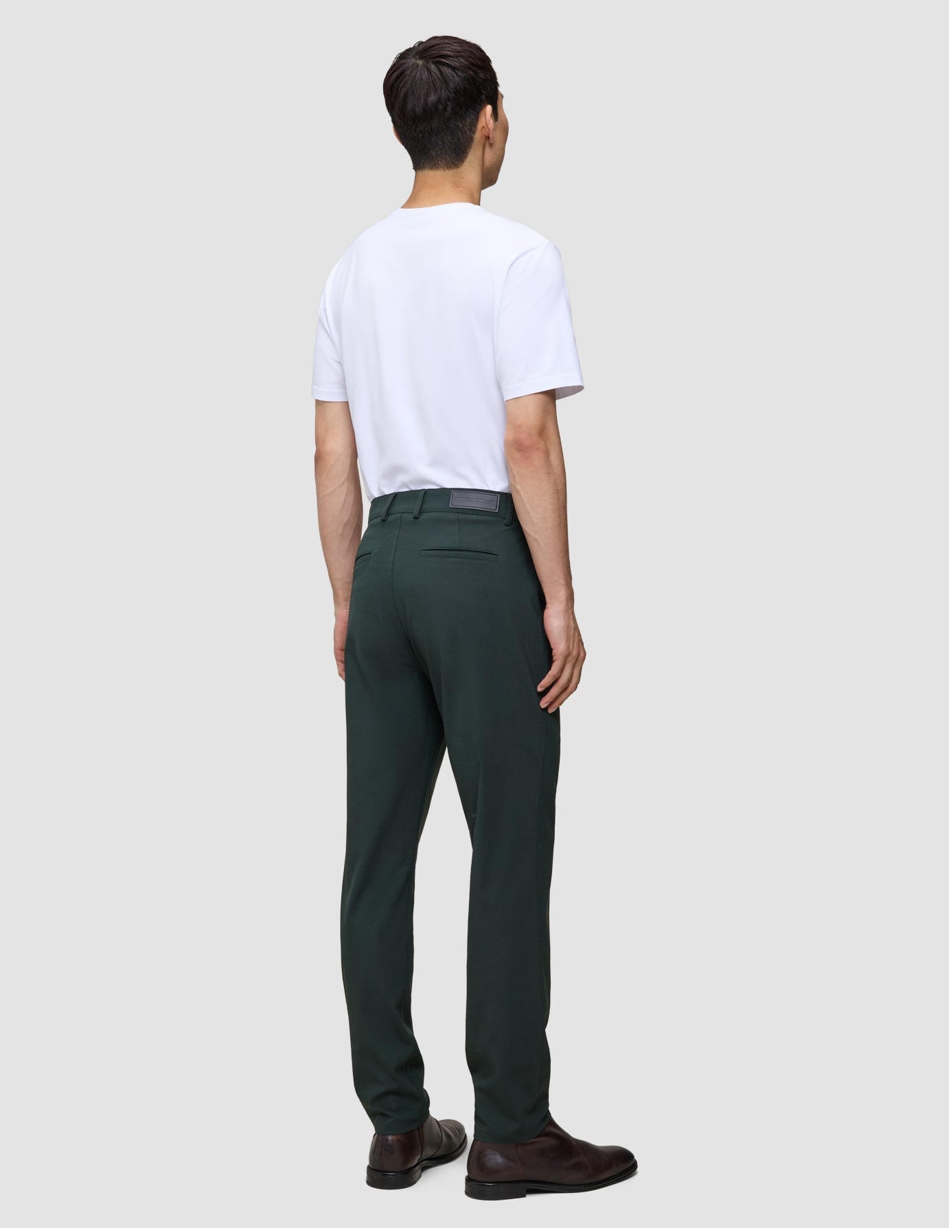 En mann sett bakfra, kledd i en hvit T-skjorte og Ease Pants Regular Northern Pine med 360°-stretch.