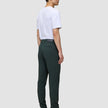 En mann sett i profil har på seg en hvit T-skjorte, Ease Pants Slim Northern Pine og brune lærstøvler, som fremhever det skandinaviske designet.